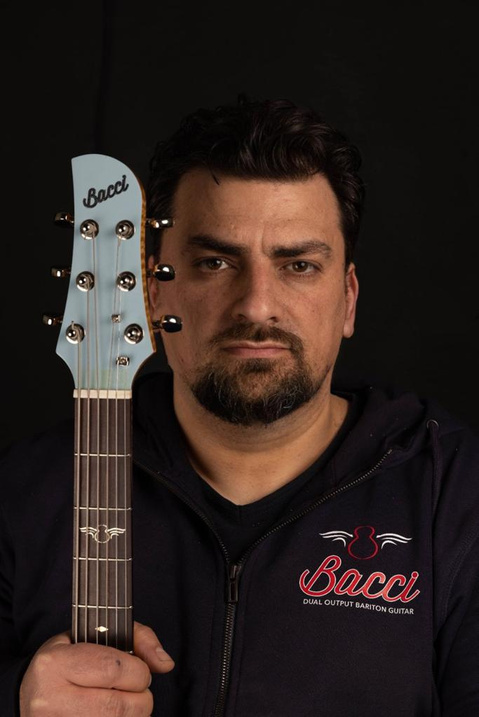 Close-up of Bruno Bacci with the neck of a Leonardo Baritone guitar beside him